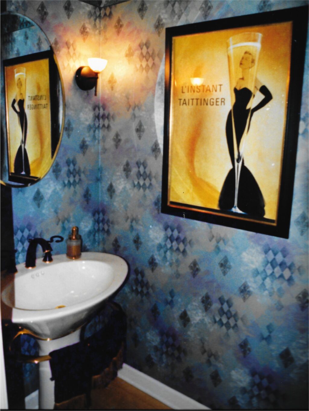 Harlequin inspired wallpaper, black and gold faucet, L'instant Taittinger framed print. Transitional interior design