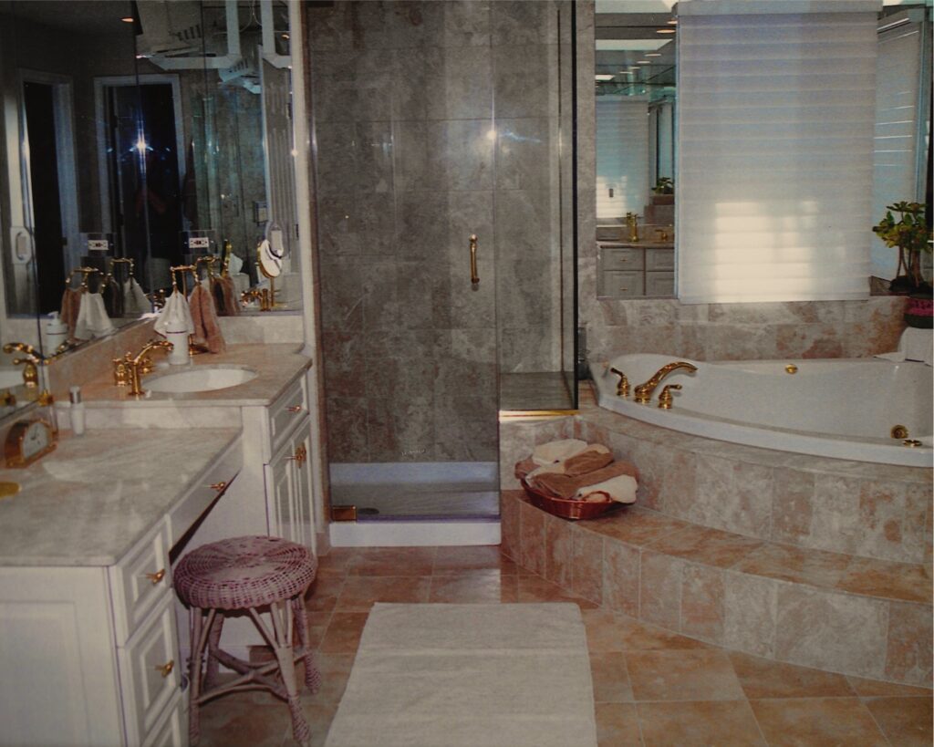 Honed Creme Marfil marble tile and counter tops, Full height mirrored walls, frameless shower enclosure, gold faucets, Hunter Douglas Duette window covering. Elegant contemporary interior design.